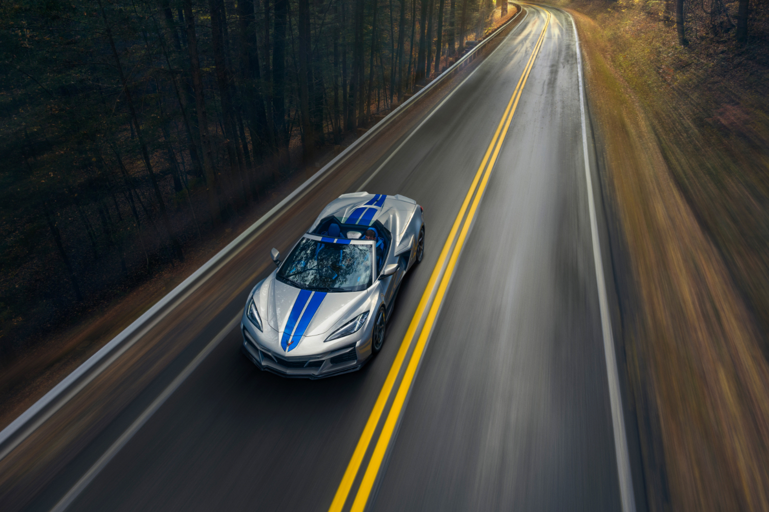 Overhead front-end angle of 2024 Chevrolet Corvette E-Ray driving down a road with the top down.