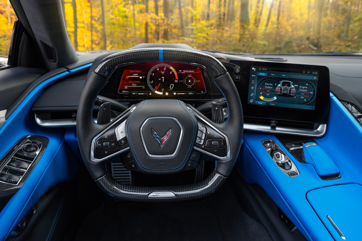Close up of steering wheel in the 2024 Chevrolet Corvette E-Ray with trees in the back.