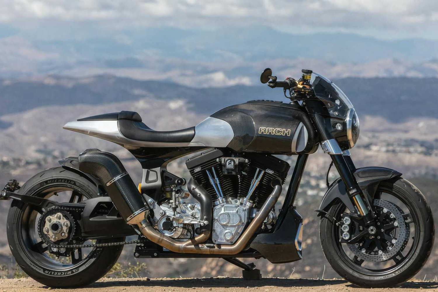 Arch Motorcycle 1s side profile parked on the side of the road with a valley in the background.