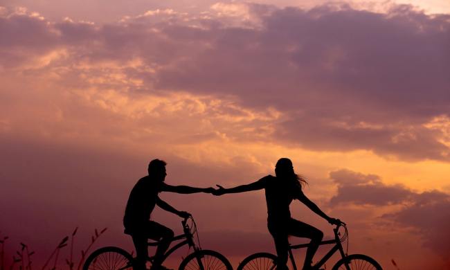 Couple riding bikes together at sunset