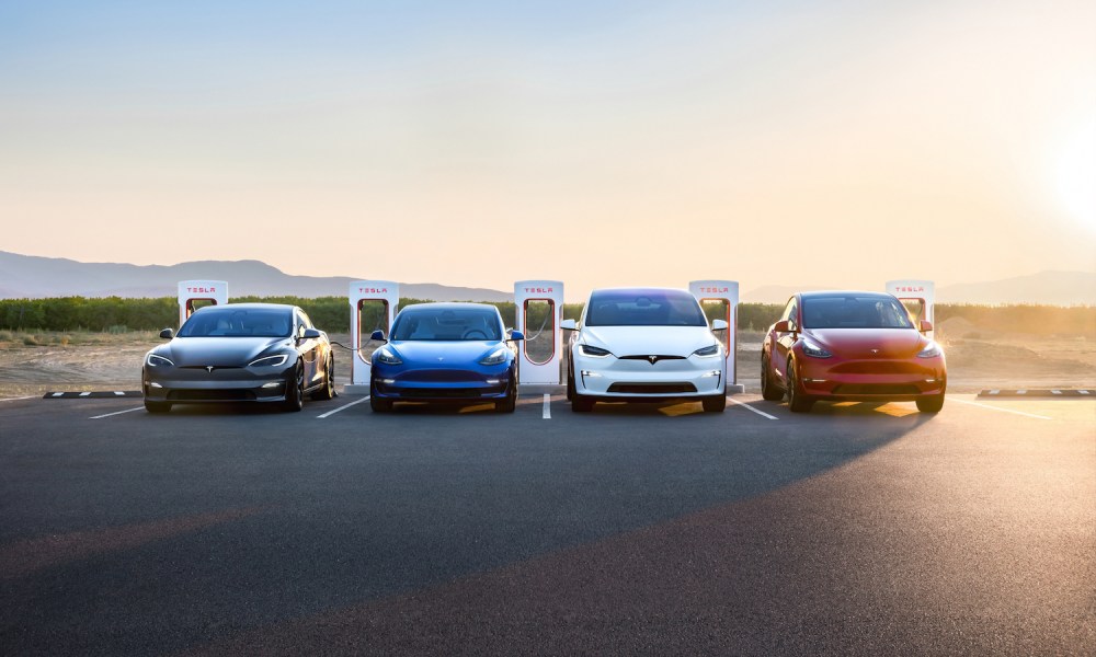 Tesla group photo with Model S, Model 3, Model X, Model Y parked in front of charger during sunset.