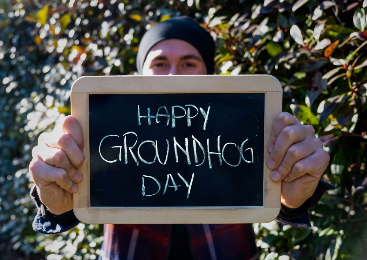 man holding a chalkboard with Happy Groundhog Day written on it