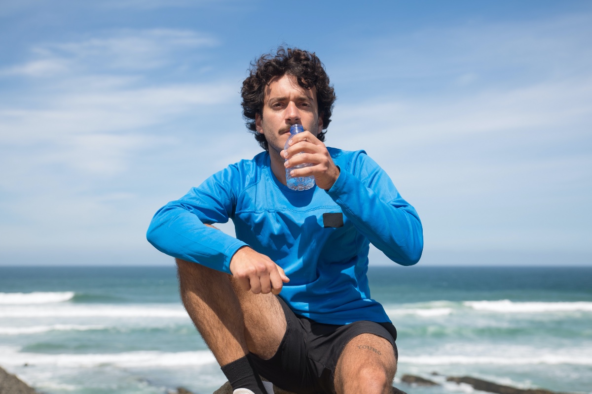 a man drinking water on the beach