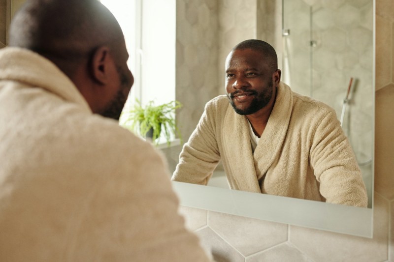 man in bathrobe smiling in the mirror