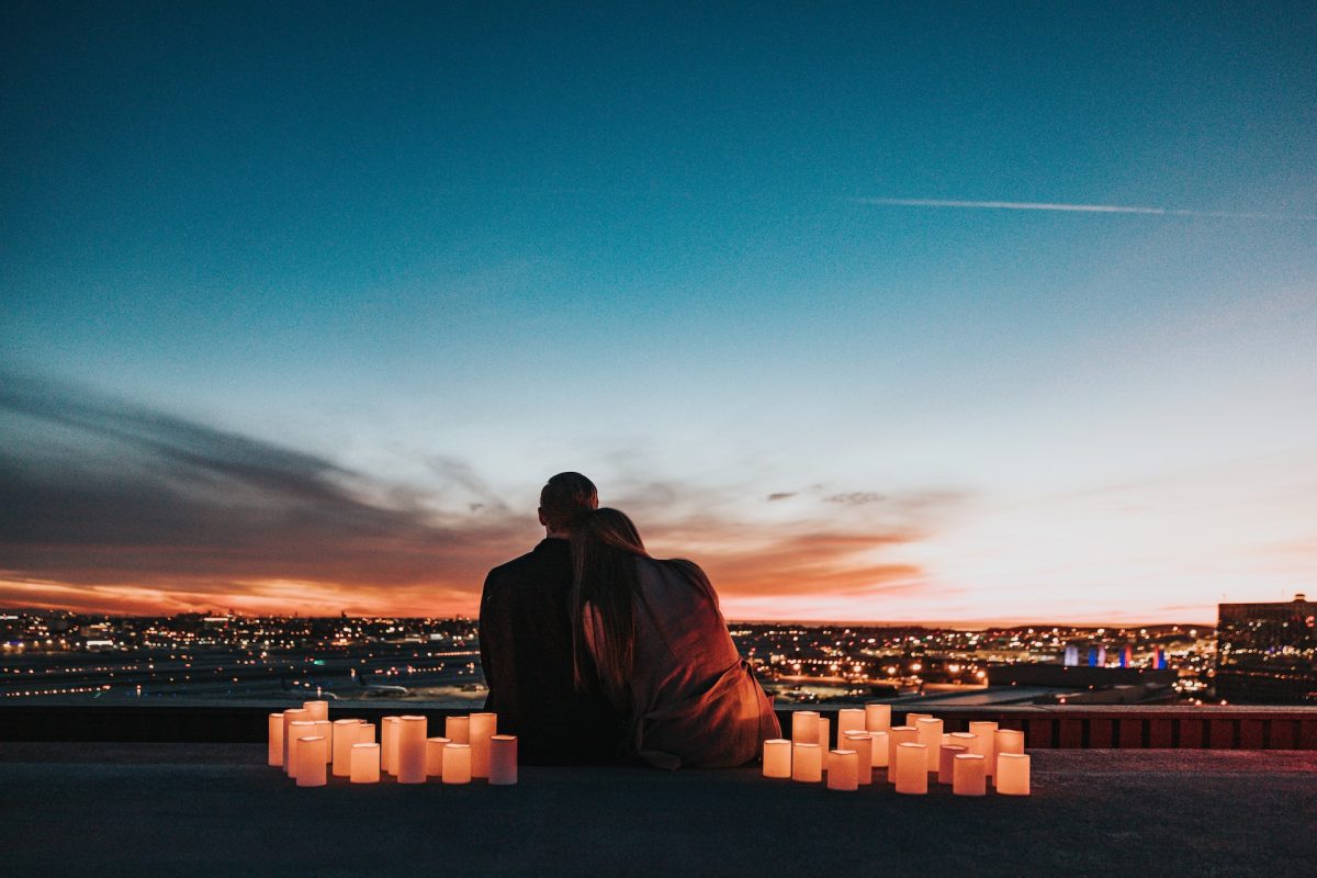 A couple on a romantic date outside with candles surrounding them.