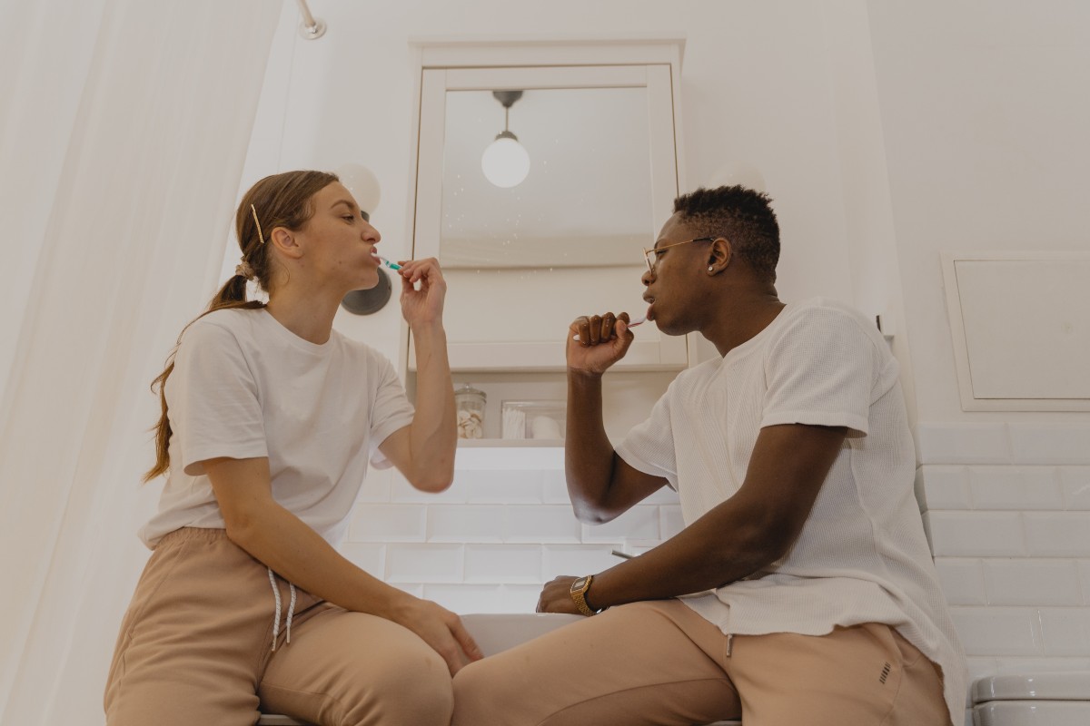 two people brushing their teeth in a bathroom