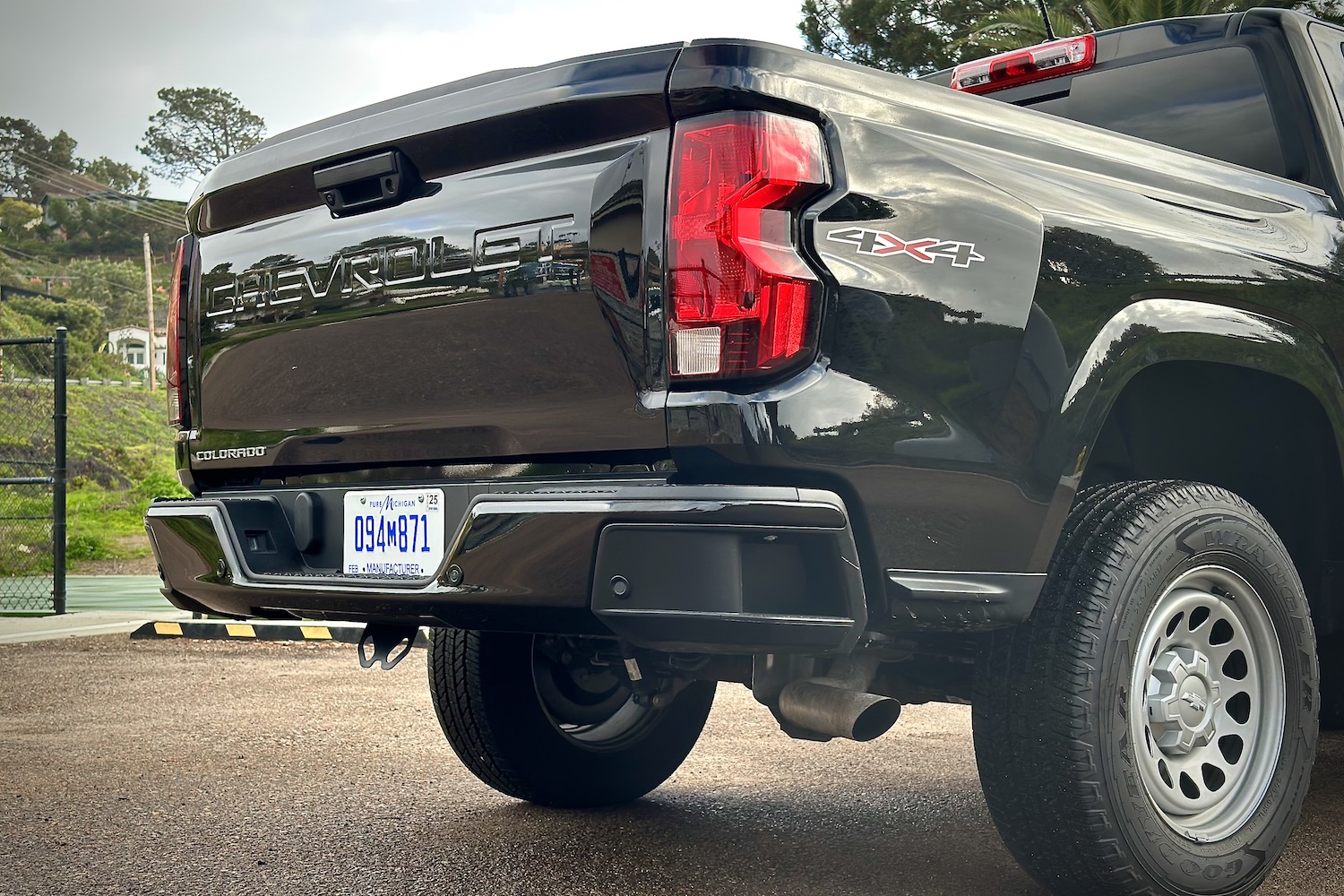 Rear end close up of the 2023 Chevrolet Colorado with taillight and rear tailgate with trees in the back.