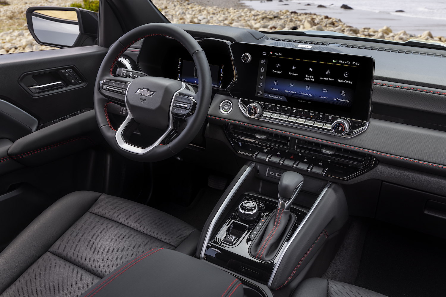 Close up of the steering wheel and dashboard in the 2023 Chevrolet Colorado Z71 trim with the ocean in the back.
