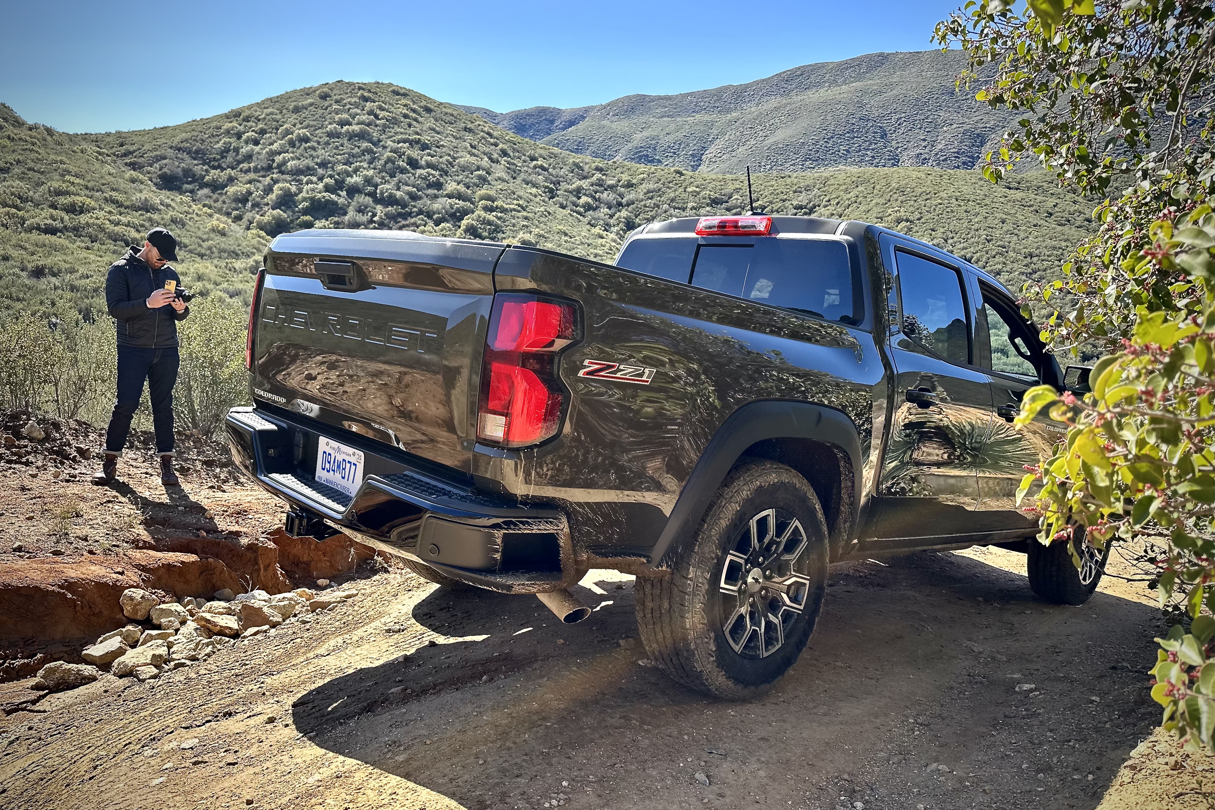 Rear end angle of the 2023 Chevrolet Colorado Trail Boss off-roading after going through an obstacle with mountains in the back.