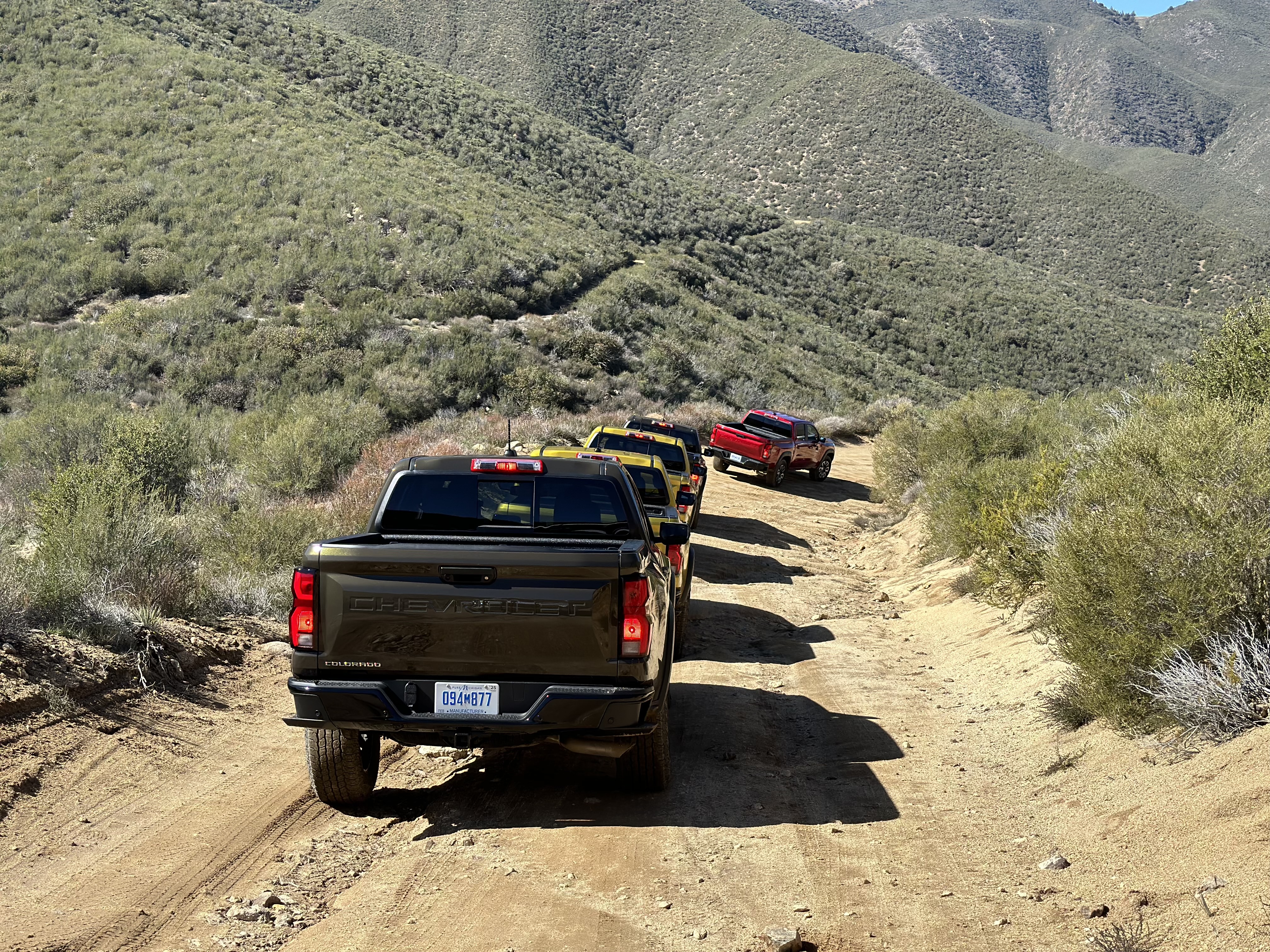 Overhead shot of the 2023 Chevrolet Colorado Trail Boss off-roading on a dirt trail with mountains in the back.