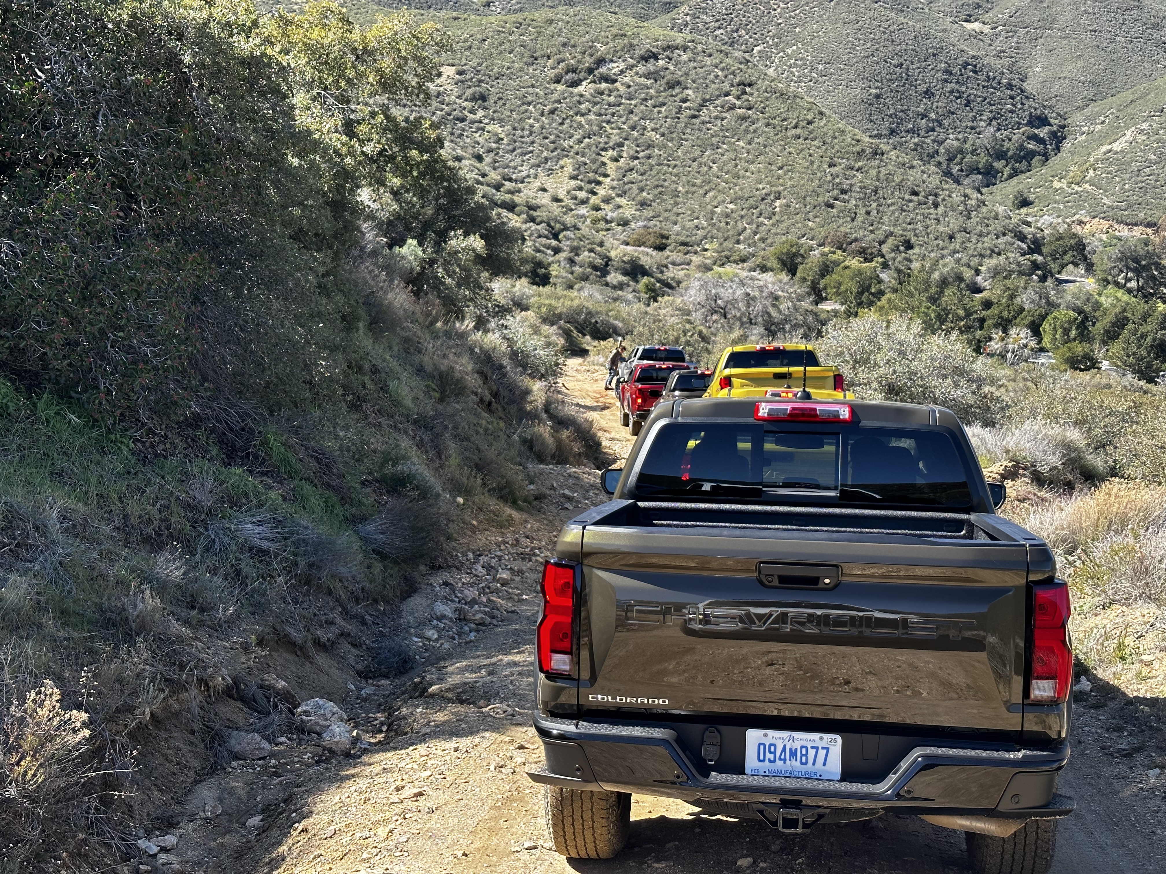 Overhead shot of the 2023 Chevrolet Colorado Trail Boss off-roading down a dirt trail with mountains in the back.