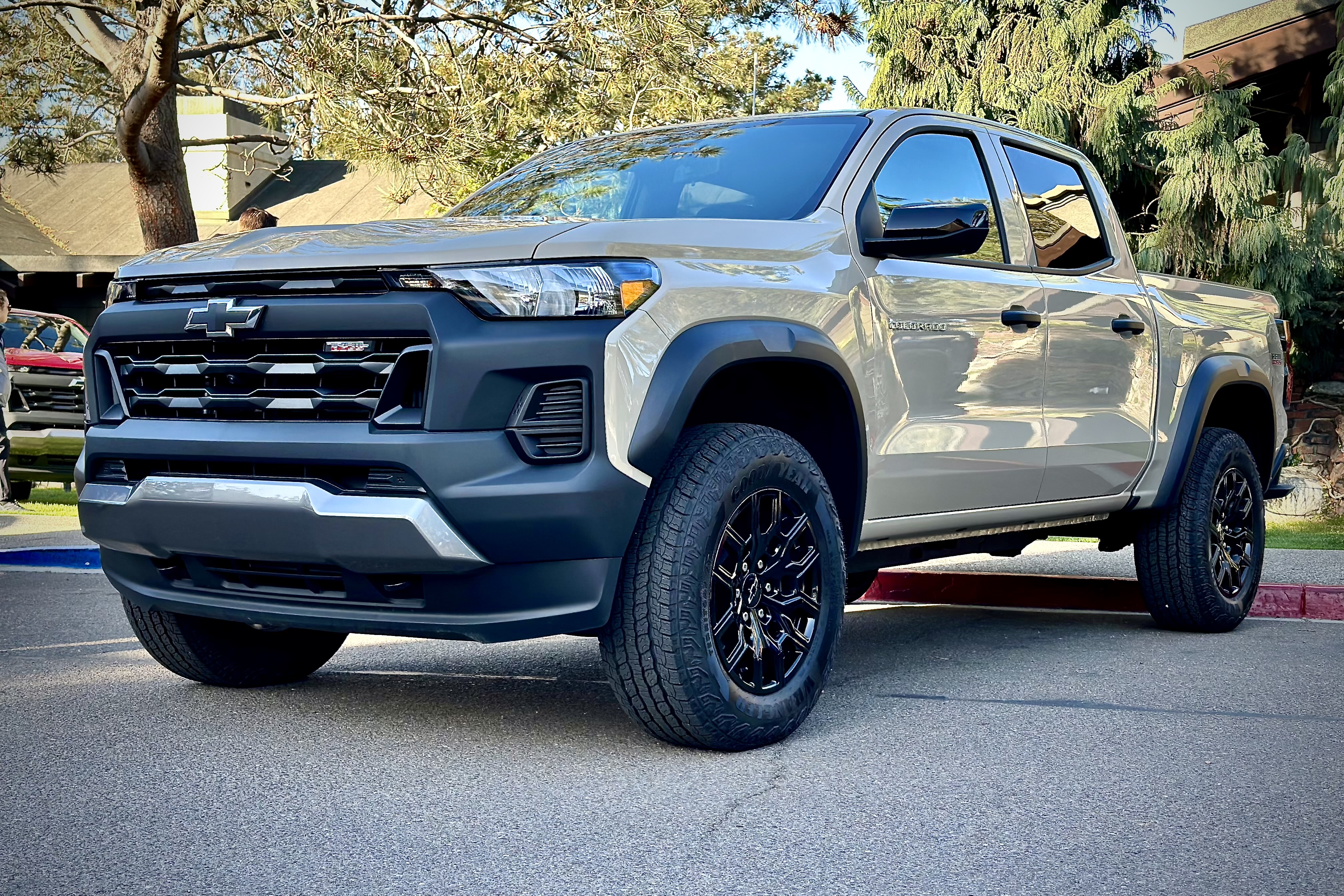 2023 Chevrolet Colorado Trail Boss front end angle parked in front of a lodge with trees.