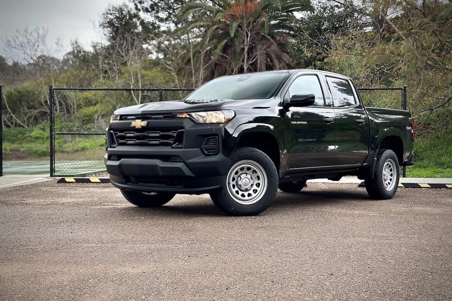 Front end angle of the 2023 Chevrolet Colorado WT from the driver's side parked in front of a tennis court.