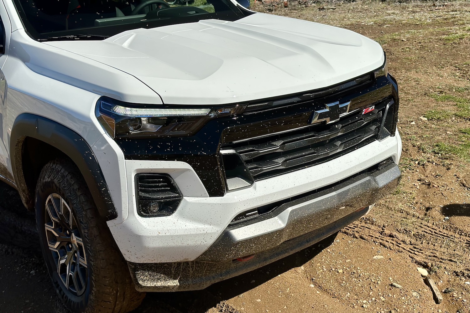 Close up of the front grille and headlights on the 2023 Chevrolet Colorado Z71 parked in a muddy field.