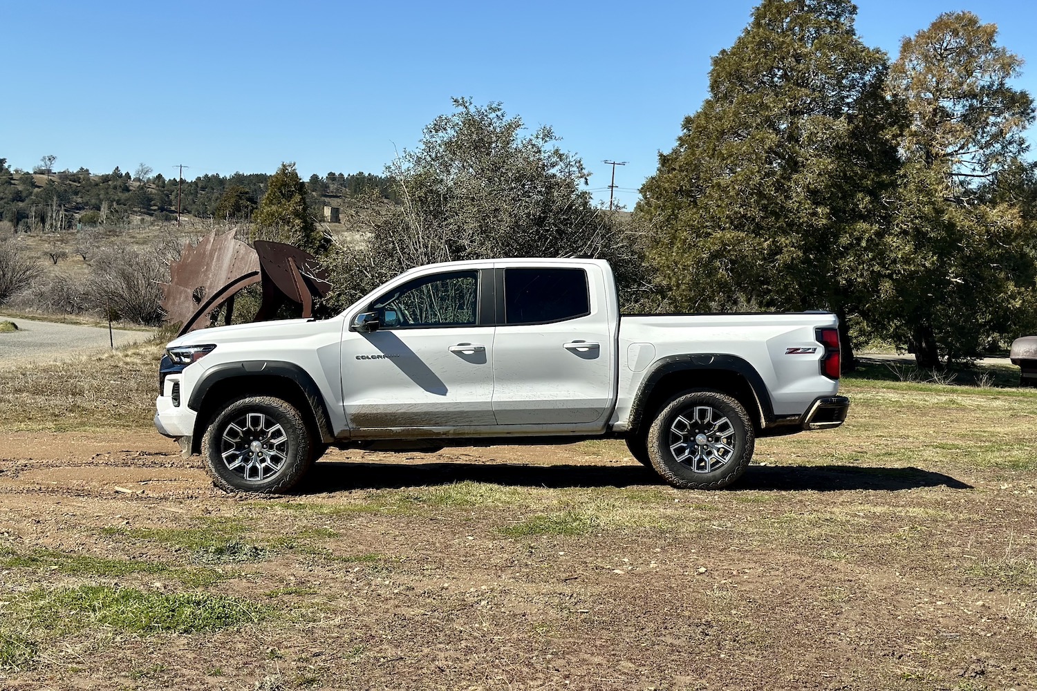 Side profile of the 2023 Chevrolet Colorado Z71 parked in a muddy field with trees in the back.