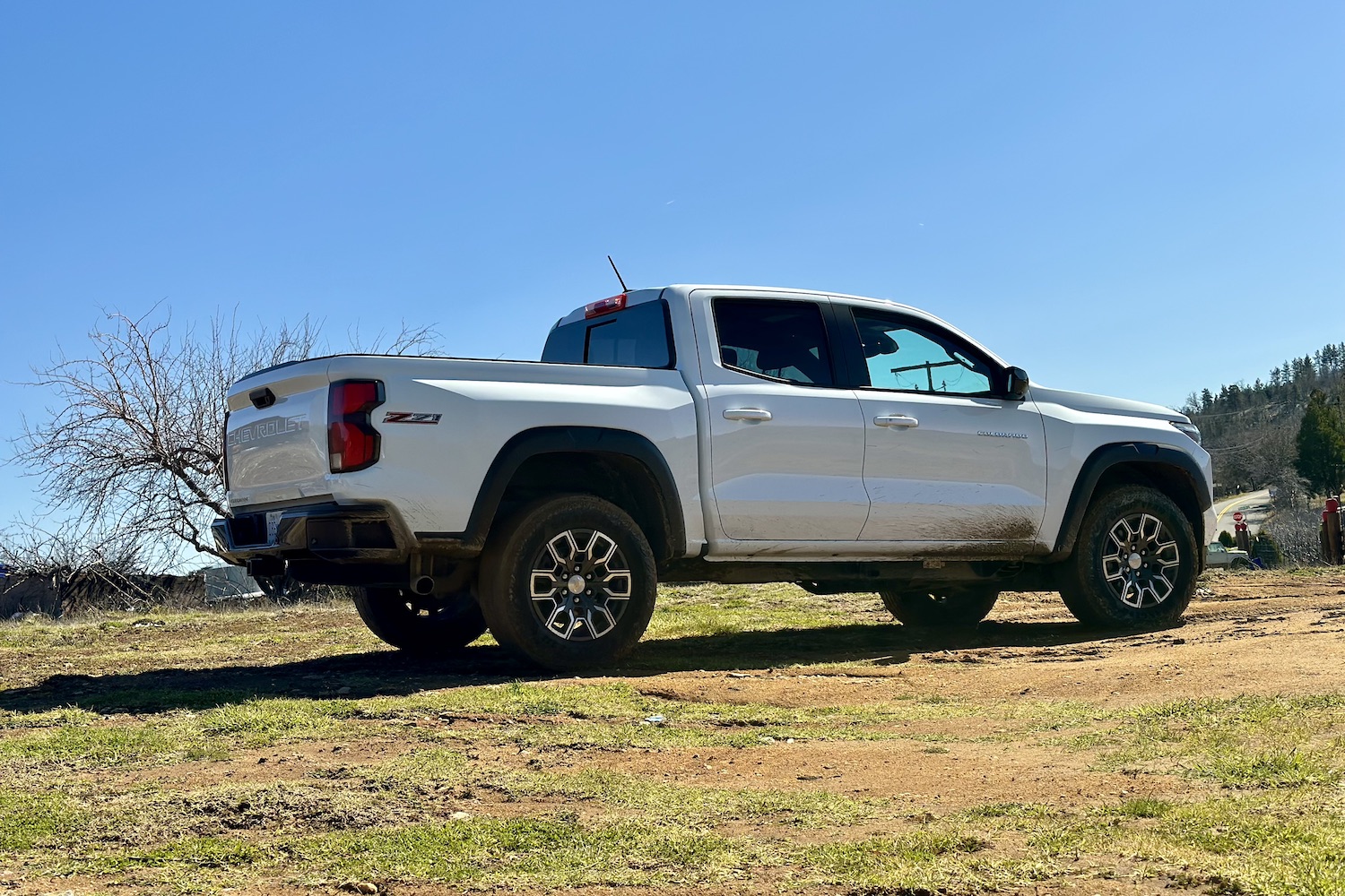 Rear end angle of the 2023 Chevrolet Colorado Z71 parked in a muddy field with trees in the back.