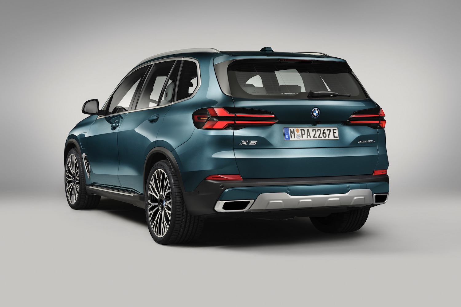 Rear end angle of the 2024 BMW X5 xDrive50e PHEV parked in a white studio.