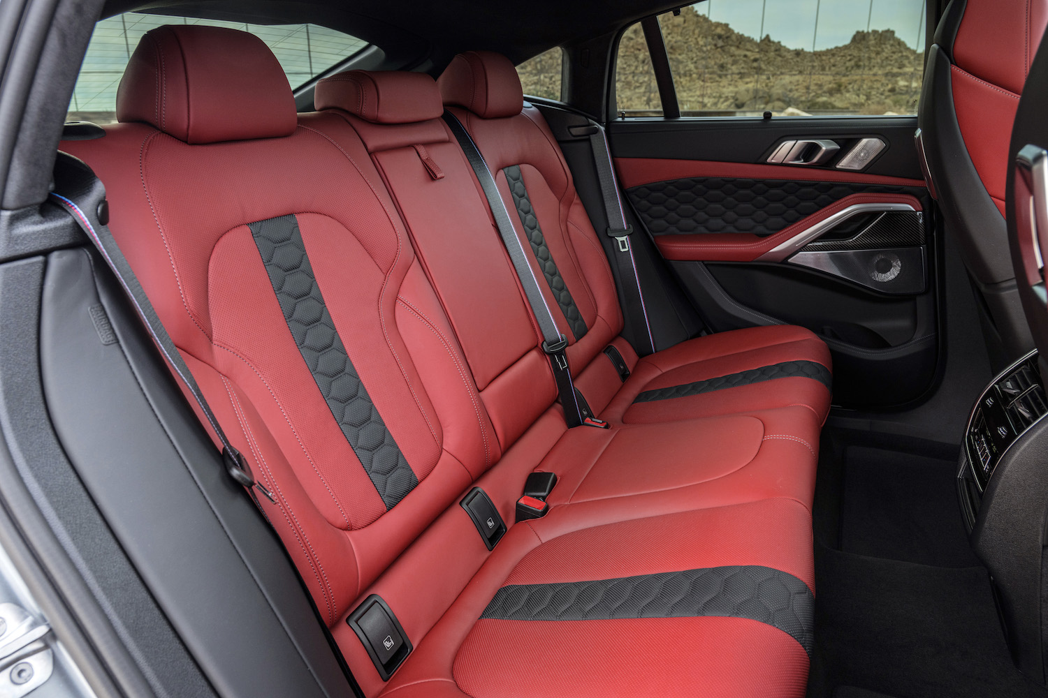 Close up of rear seats in the 2024 BMW X6 M Competition from outside the SUV with desert in the back.