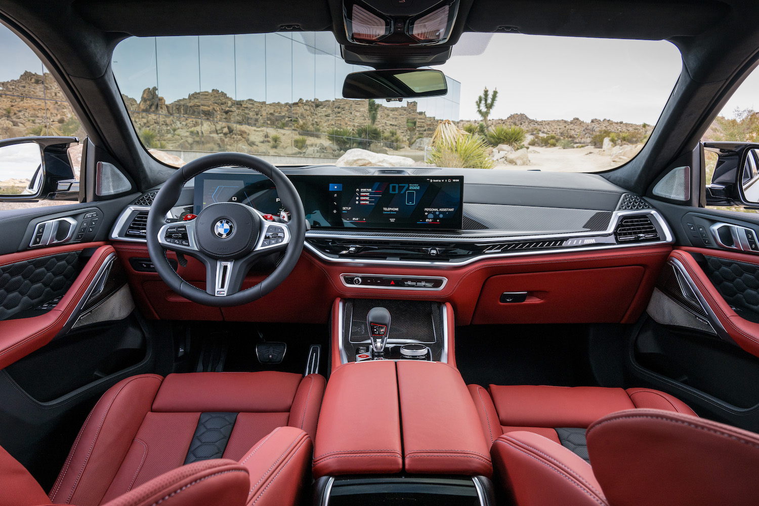 Dashboard in the 2024 BMW X6 M Competition from the rear seats with the desert in the back.