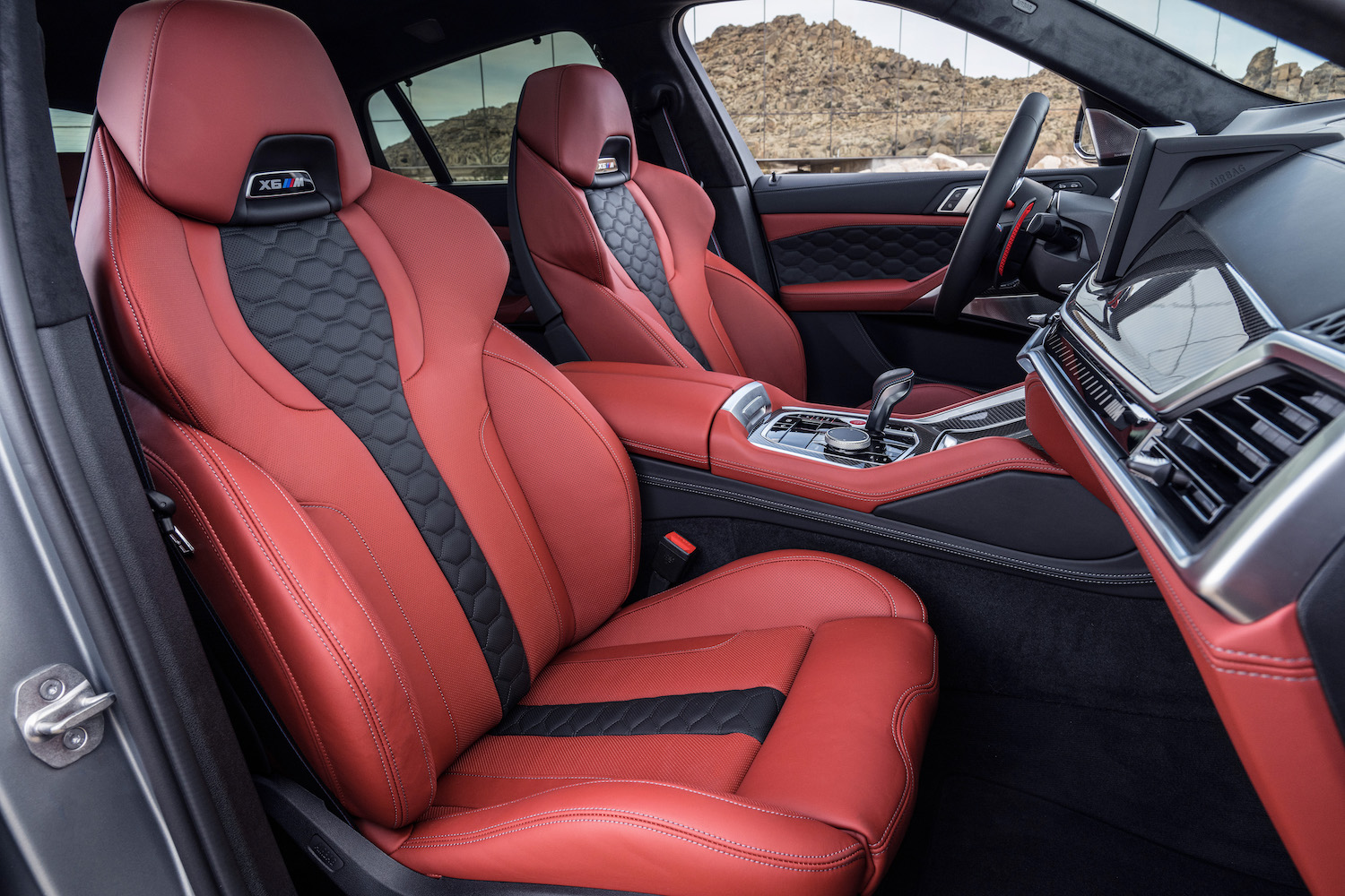 Close up of front seats in the 2024 BMW X6 M Competition from outside the SUV with desert in the back.