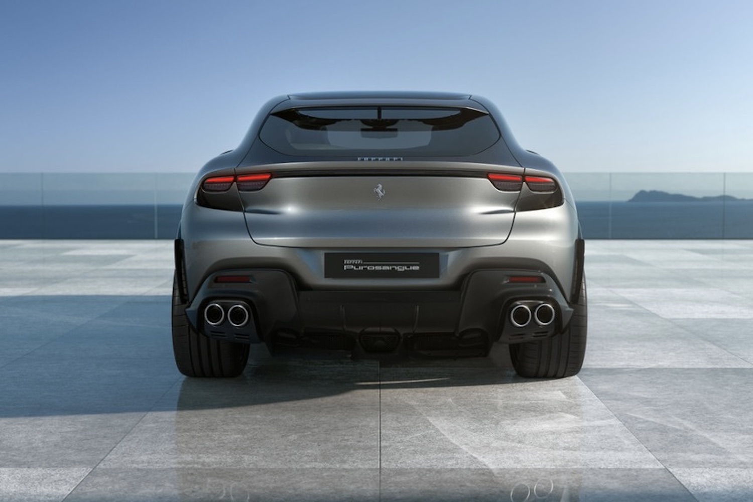 Rear end close up of the 2024 Ferrari Purosangue parked on a parking pad in front of water.