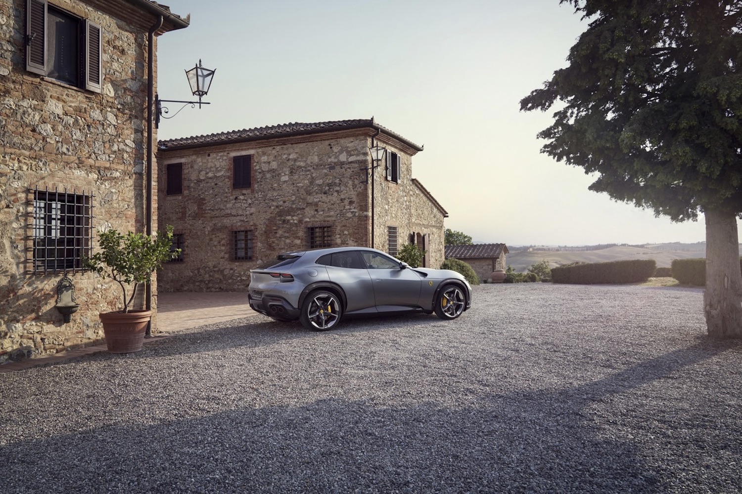 2024 Ferrari Purosangue rear end angle from passenger's side parked in front of old stone buildings.