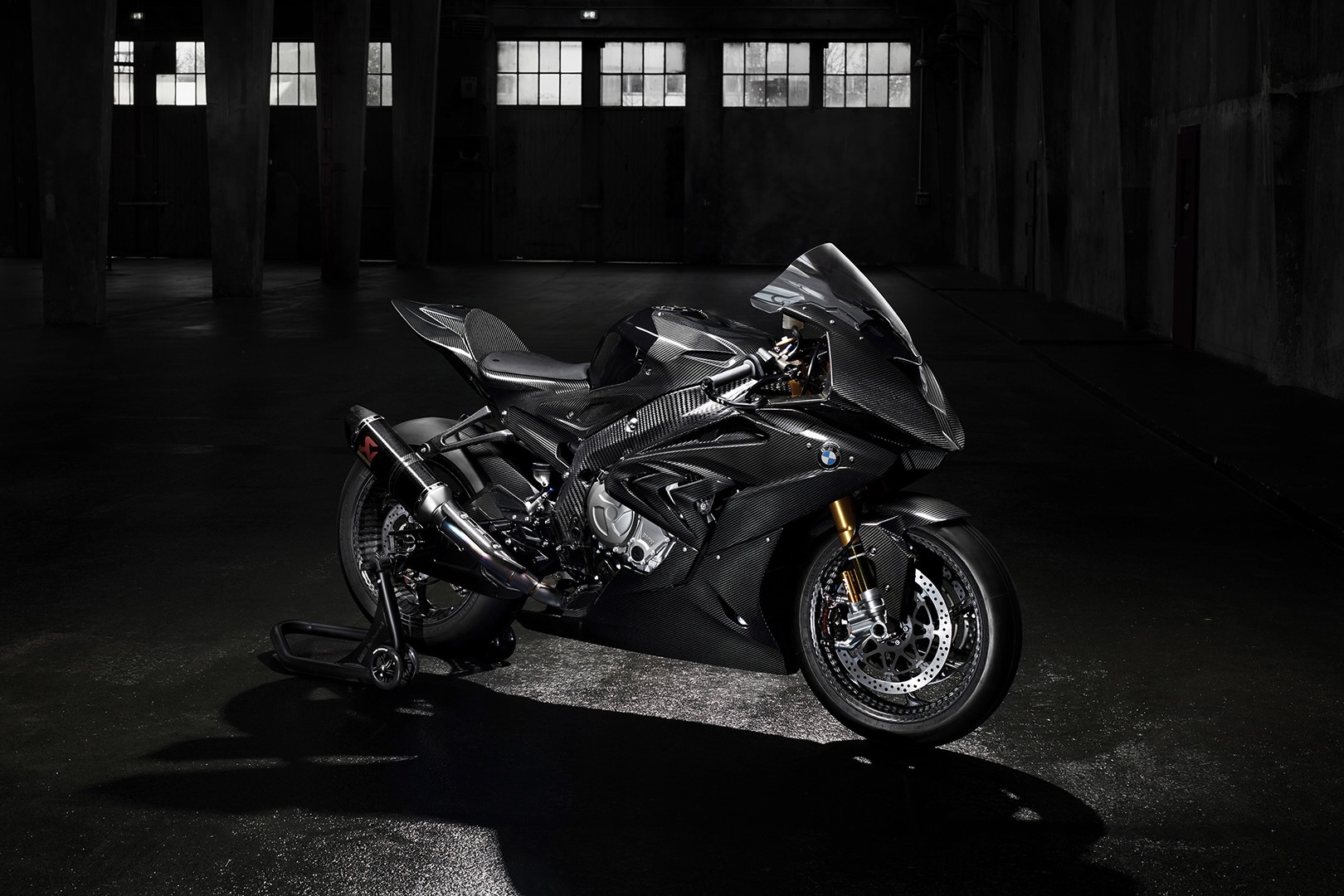 BMW HP4 Race finished in bar carbon fiber in a studio with dark lighting.