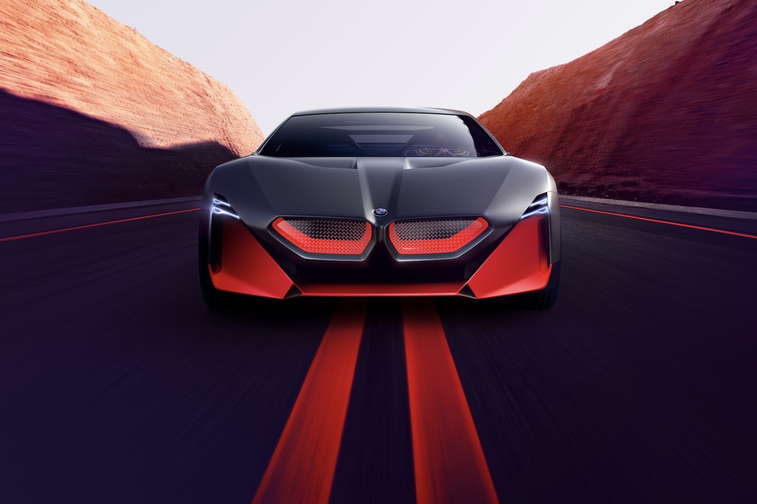 Close up of the front end of BMW M Vision NEXT Concept driving down the road with mountains in the back.