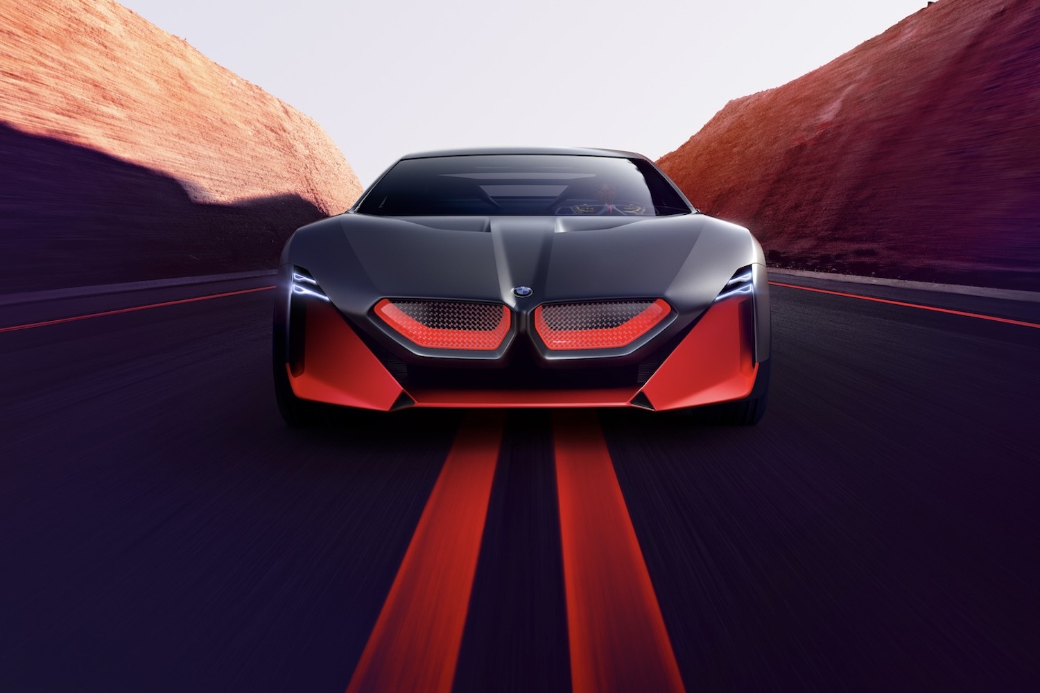 Close up of the front end of BMW M Vision NEXT Concept driving down the road with mountains in the back.