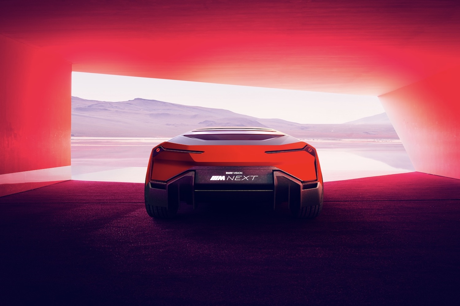 BMW M Vision NEXT Concept close up of rear end parked in a red garage with mountains in the back.