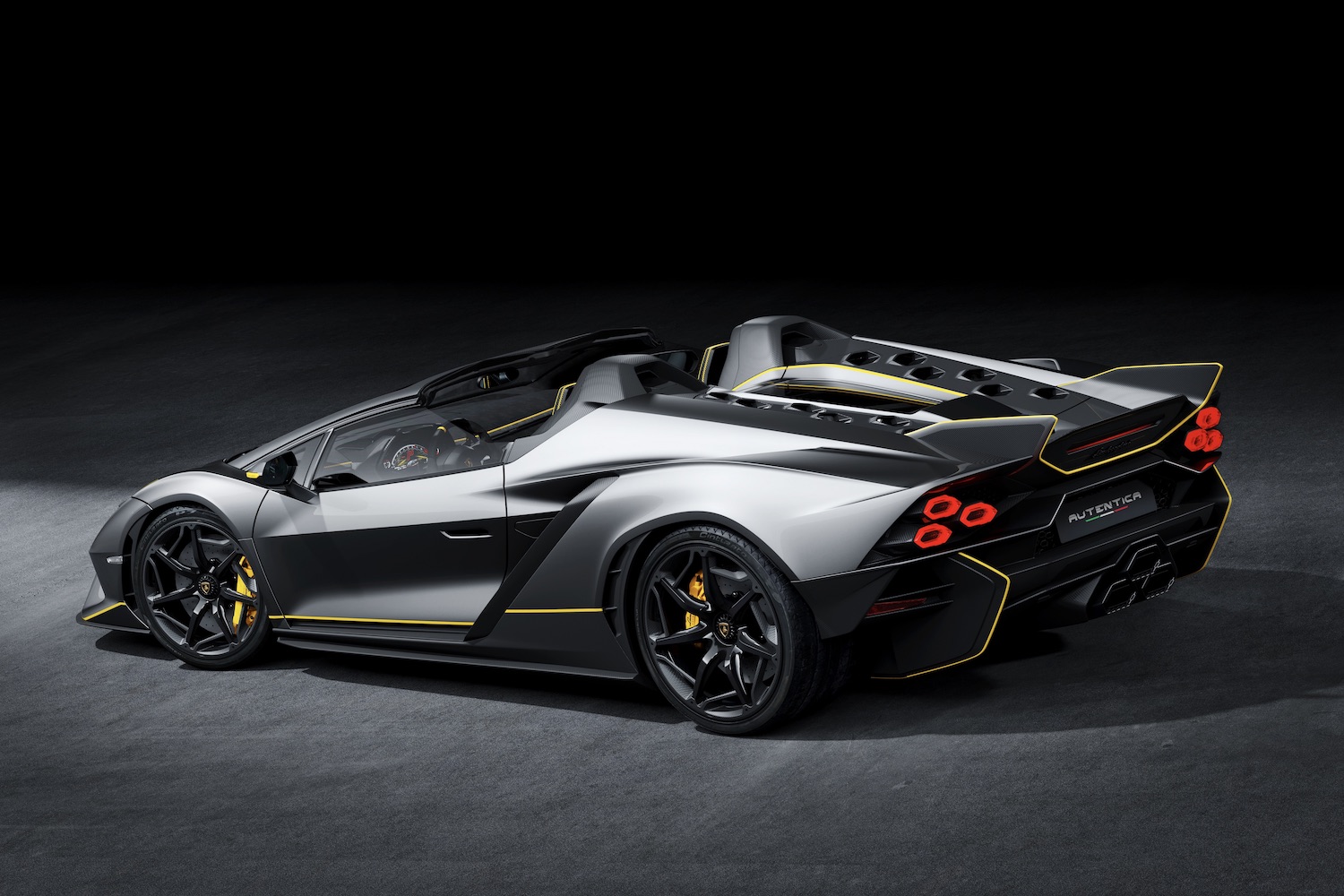 Rear end angle of Lamborghini Auténtica from driver's side in a dark studio with studio lighting.