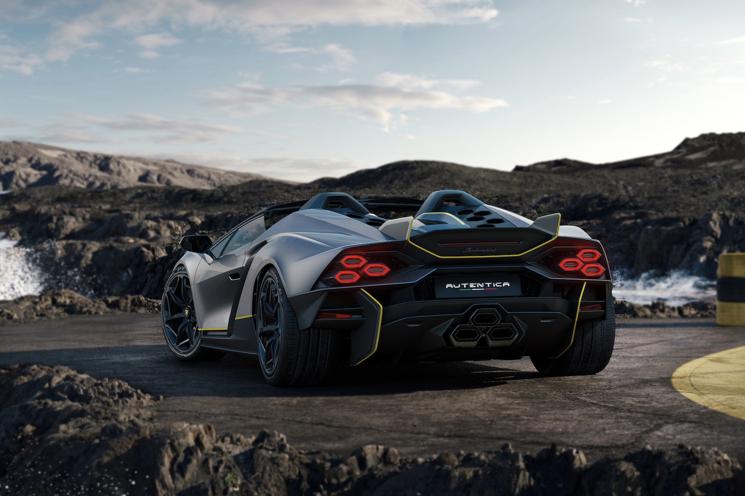 Lamborghini Auténtica rear end angle parked on the side of a windy road in front of cliffs and water.