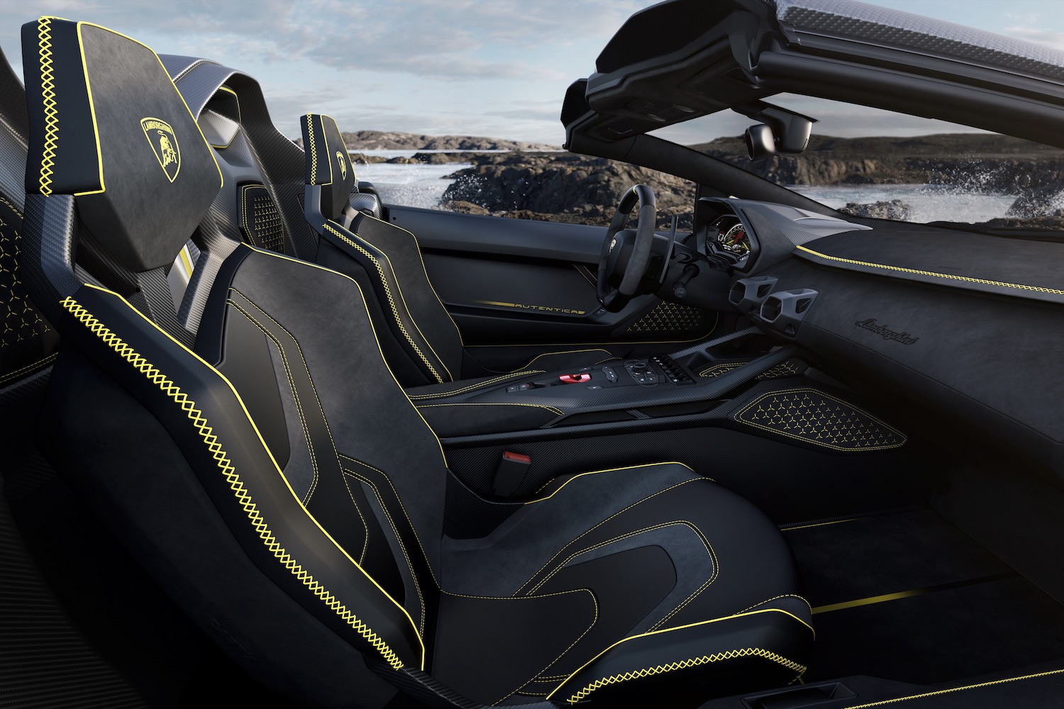 Front seats in the Lamborghini Auténtica from the passenger side outside the car with cliffs and water in the back.