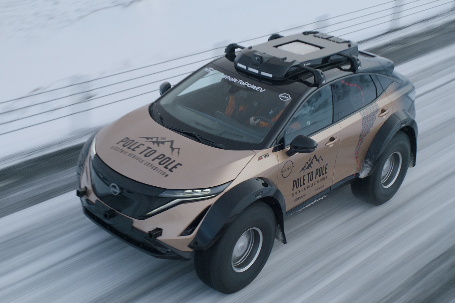 Nissan Ariya overhead front end shot of electric SUV driving down an icy road.