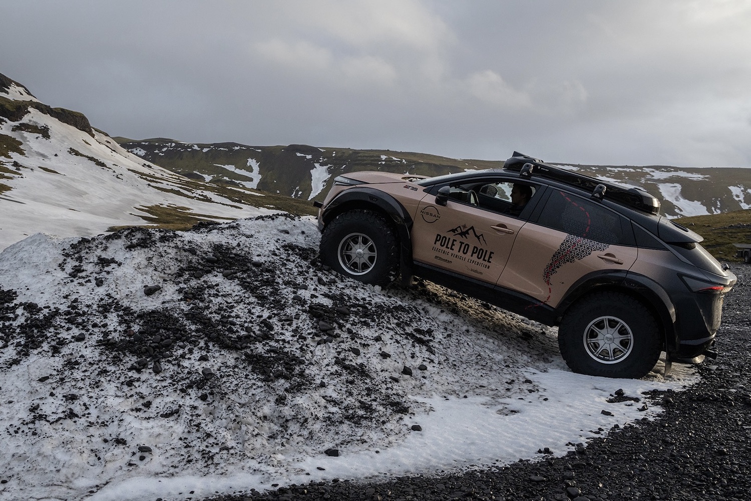 Side profile of Nissan Ariya climbing sharp rocks on icy terrain.