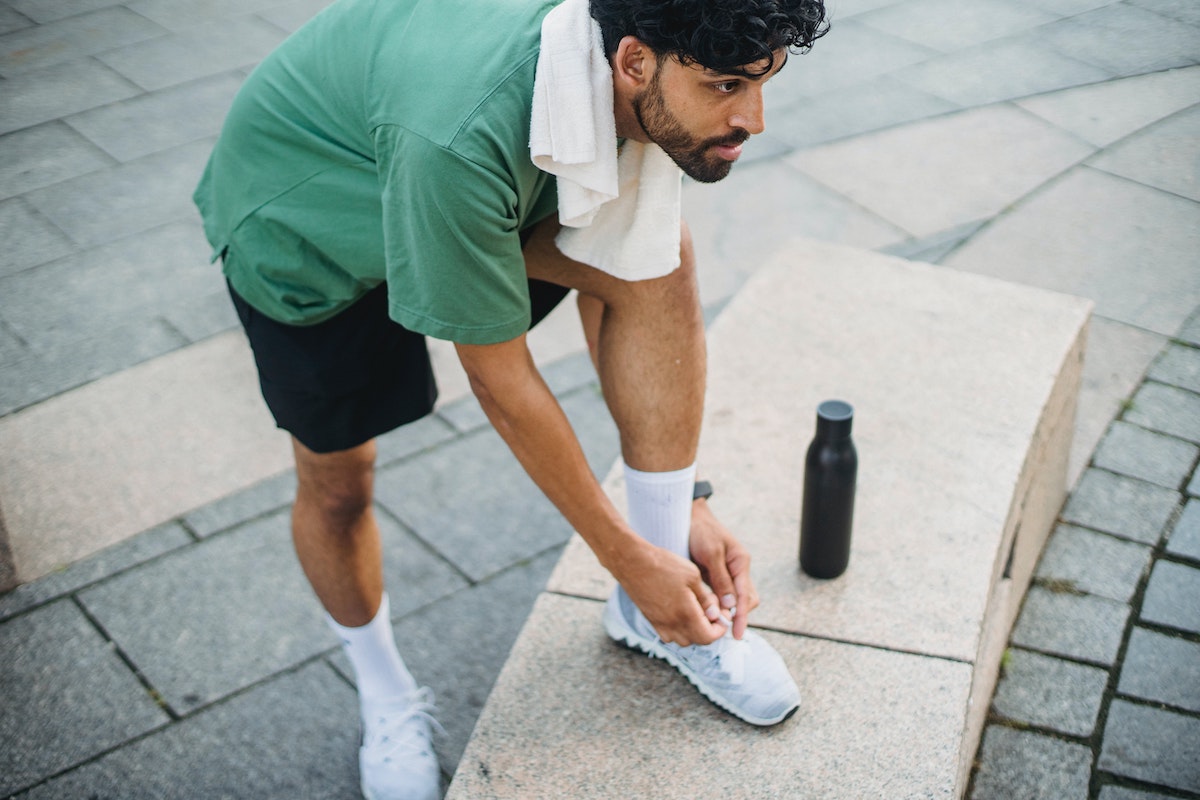 man tying sneakers outside