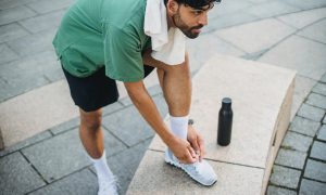 Man tying his sneakers outside