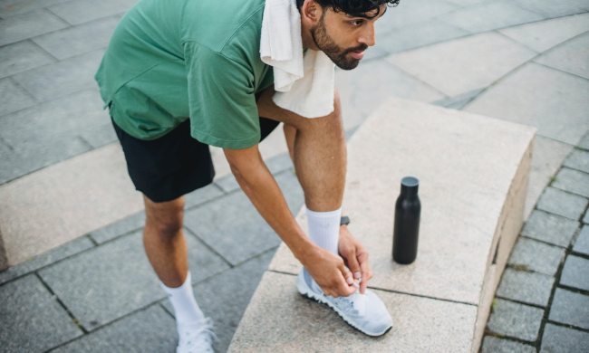 man tying sneakers outside