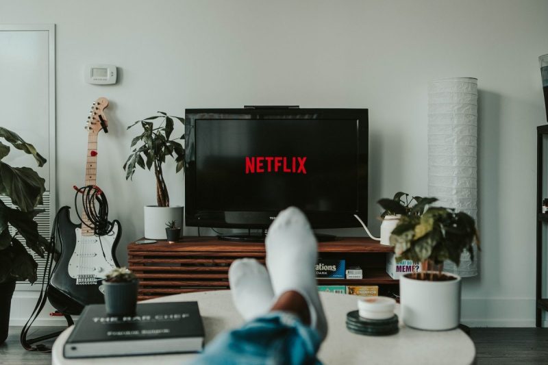 A person sitting in the living room with their feet up watching Netflix.
