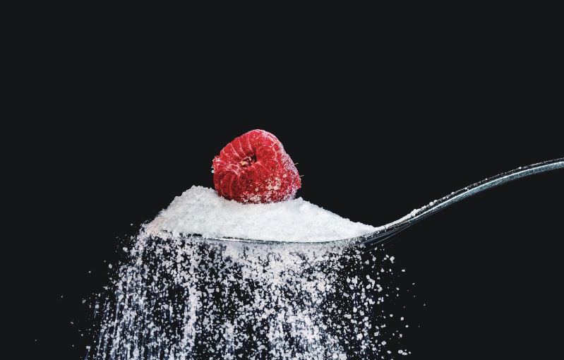 Spoon with sugar and a raspberry