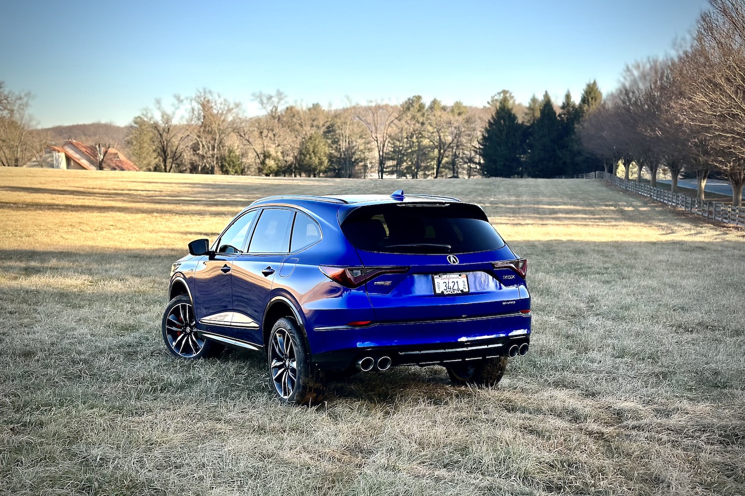 2022 Acura MDX Type S rear end angle from driver's side parked in a hay field during sunset with trees in the back.