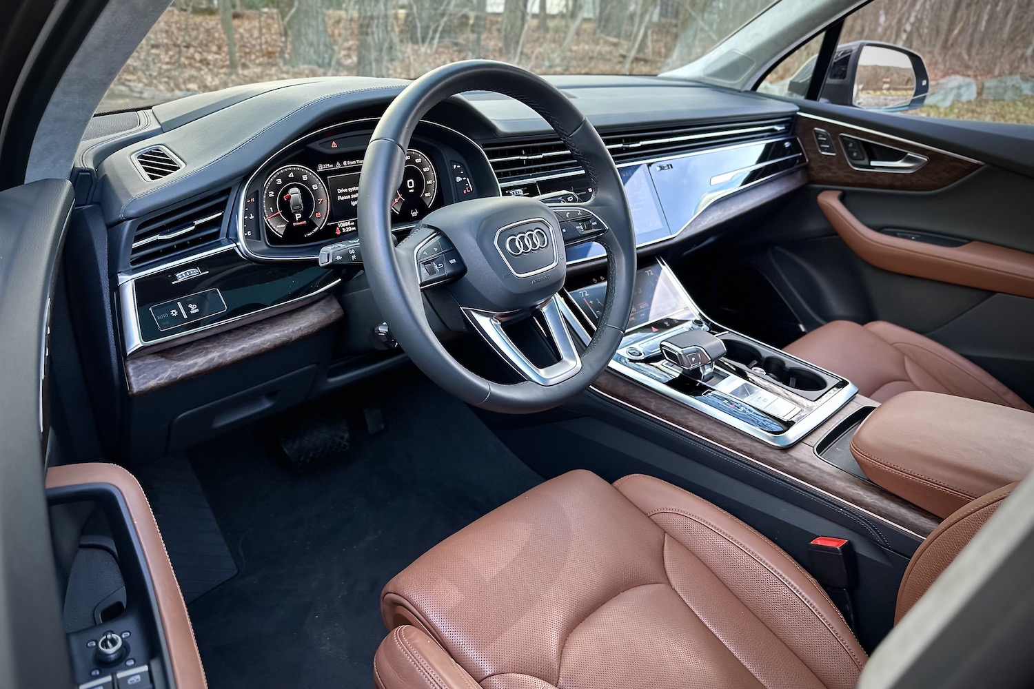 Close up of dashboard and steering wheel in the 2022 Audi Q7 Prestige with trees in the back.