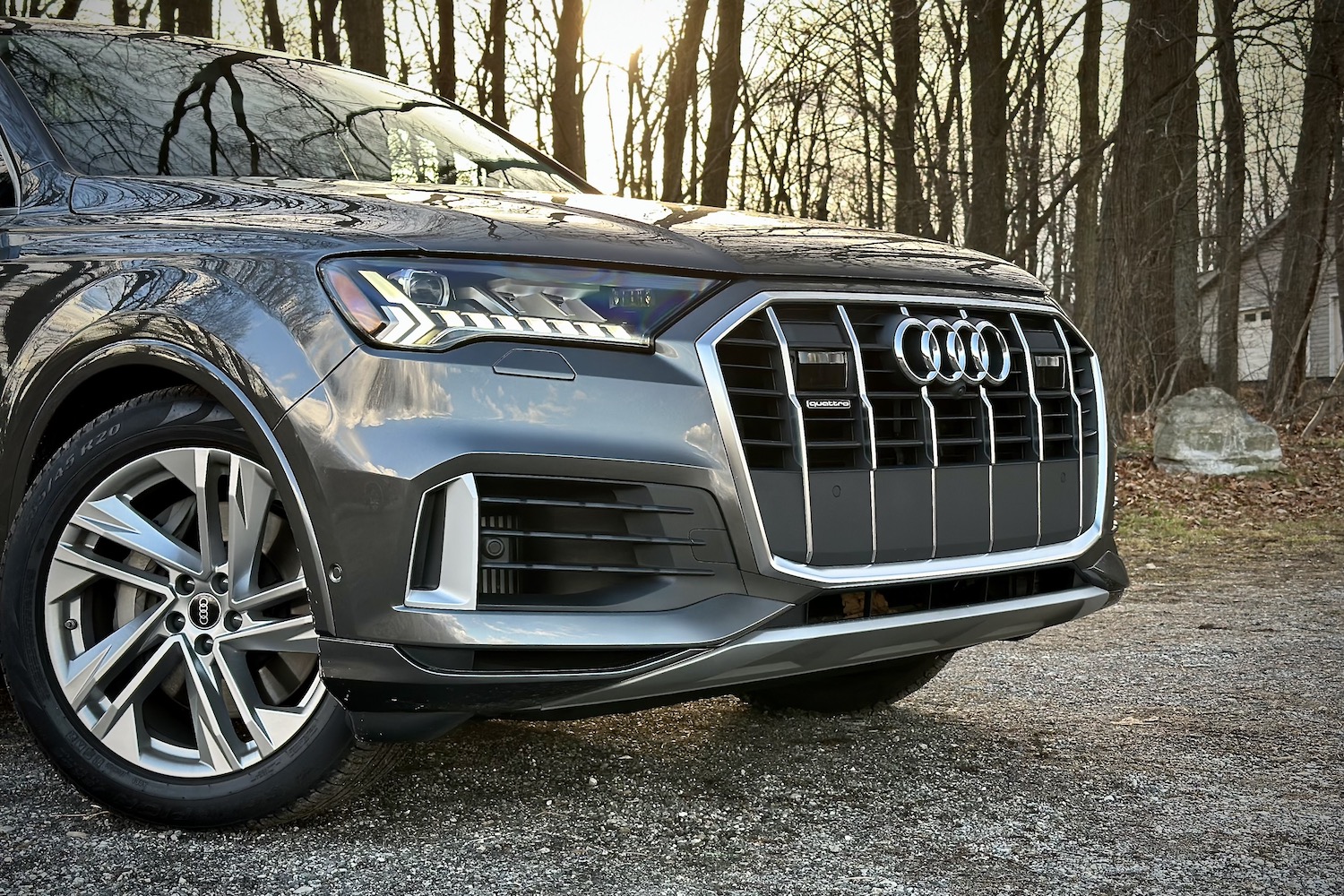 Close up shot of the 2022 Audi Q7 Prestige's front end parked on a gravel lot in front of trees.
