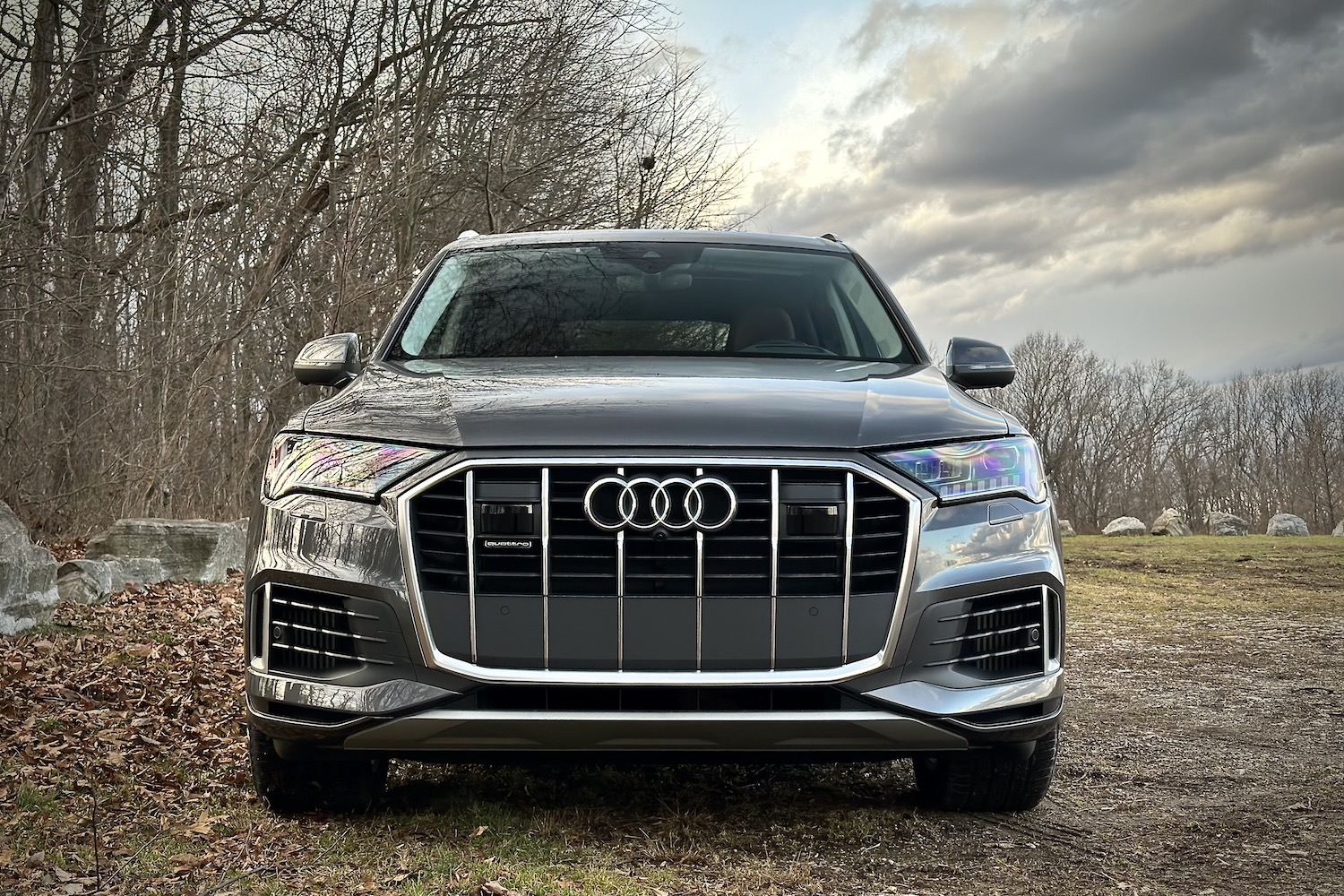 Close up of front end of the 2022 Audi Q7 Prestige parked in a grassy field with trees in the back.
