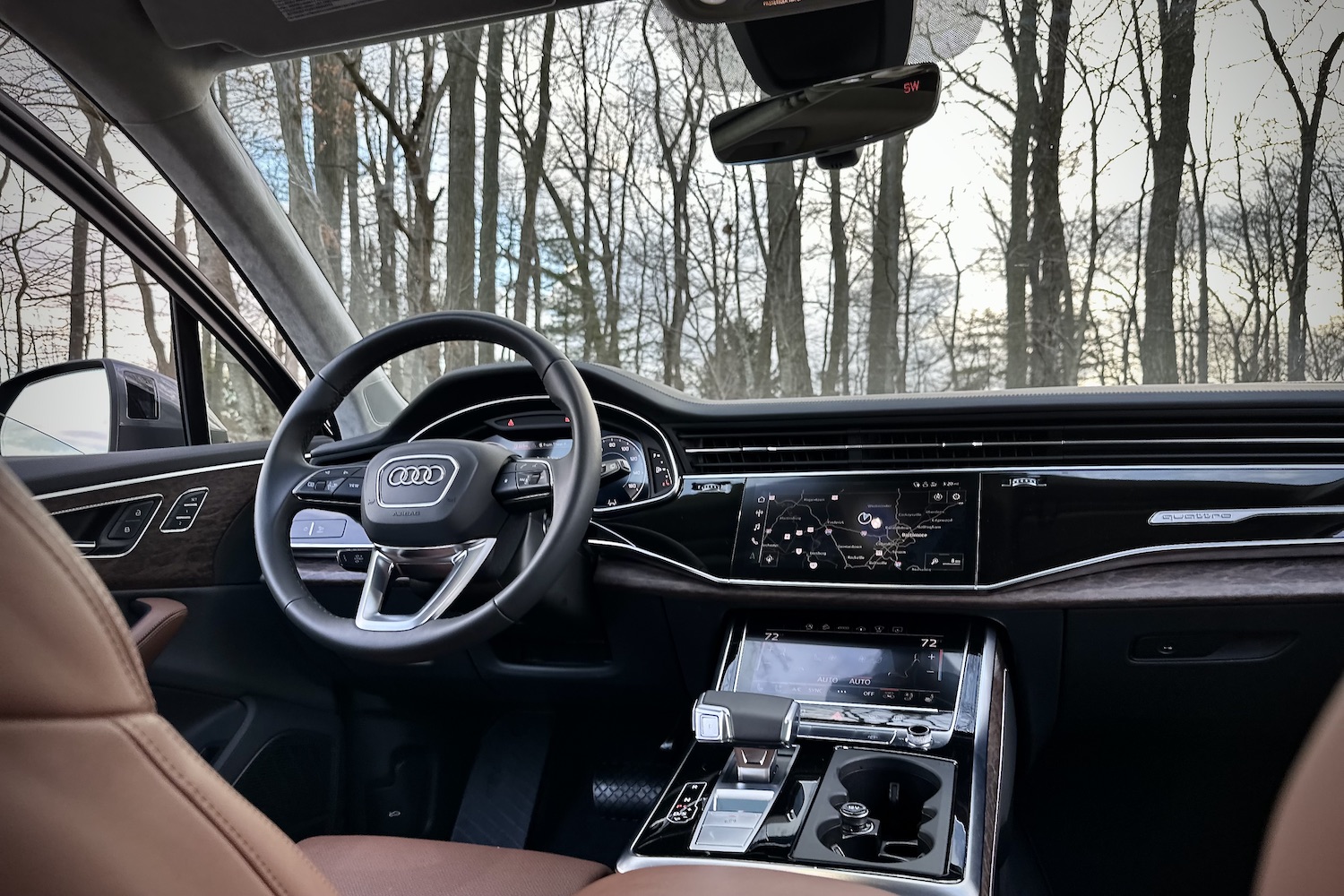 Close up of dashboard and steering wheel in the 2022 Audi Q7 Prestige with trees in the back.