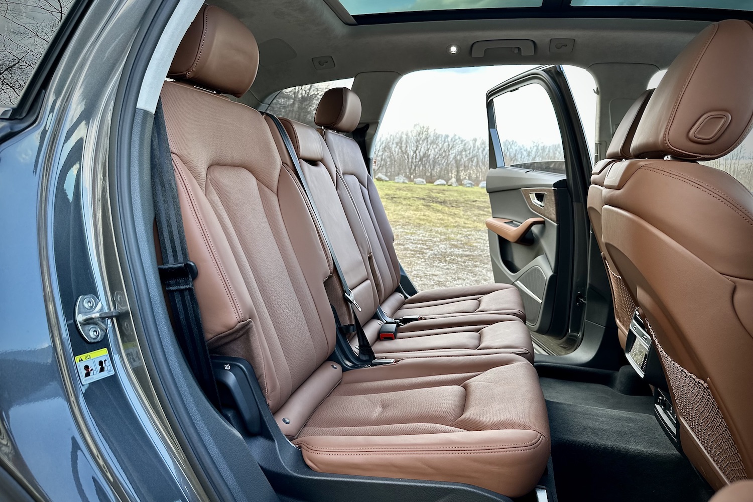 Second-row seats in the 2022 Audi Q7 Prestige with the doors open in a grassy field.