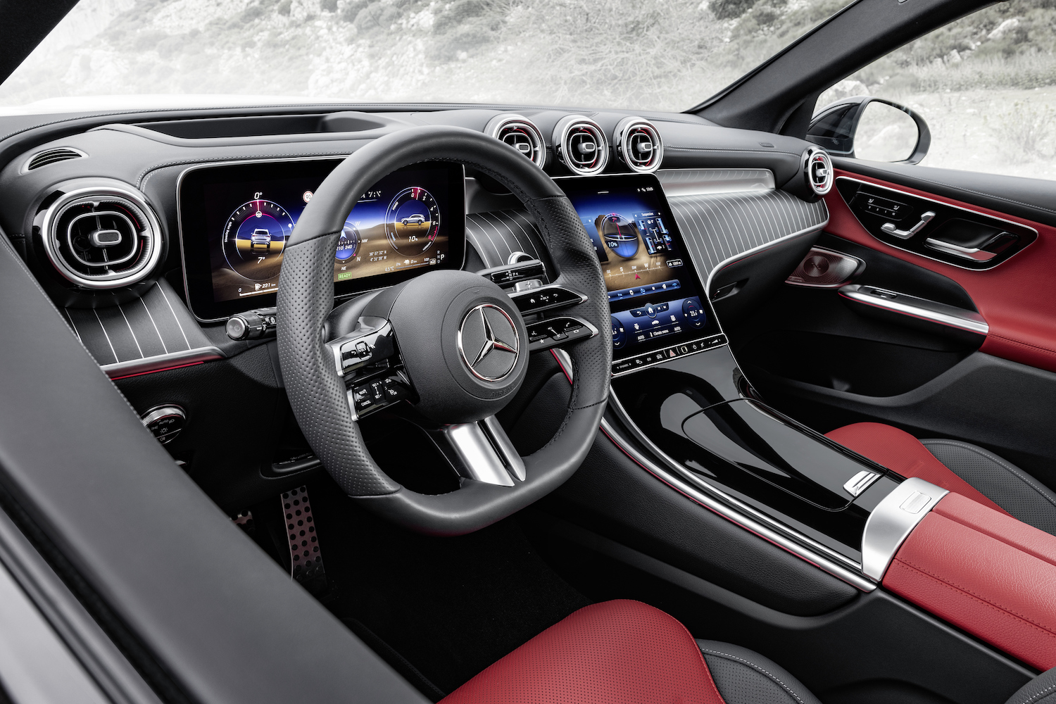 Close up of steering wheel in the 2023 Mercedes-Benz GLC from outside the driver's side in front of mountains.