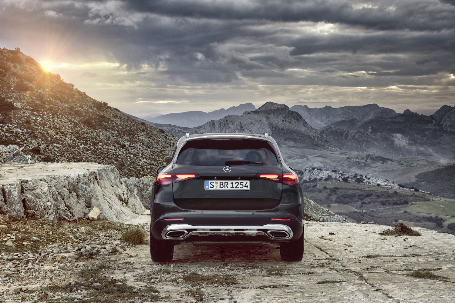 Rear end close up of the 2023 Mercedes-Benz GLC parked in front of mountains during sunset.