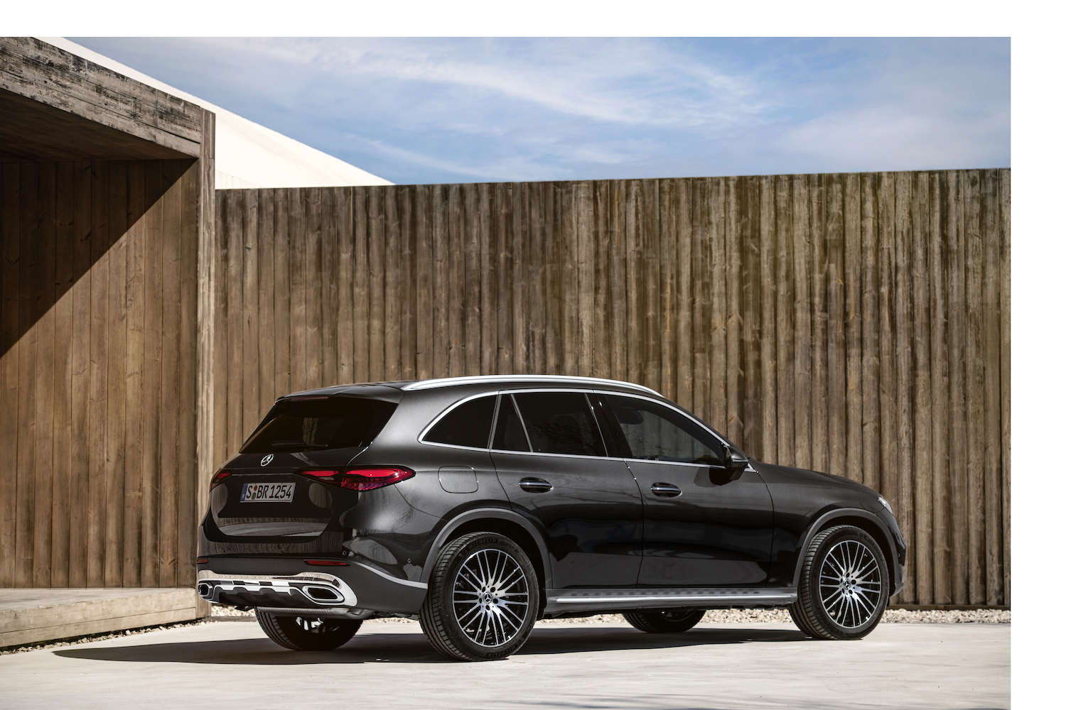 2023 Mercedes-Benz GLC rear end angle from the passenger's side parked in front of a tall wooden fence.