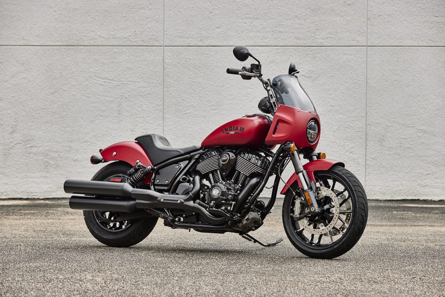 2023 Indian Sport Chief front end angle with optional handlebar lifters parked in front of a concrete wall.